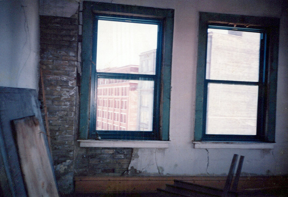 Two windows look out over a red brick building.