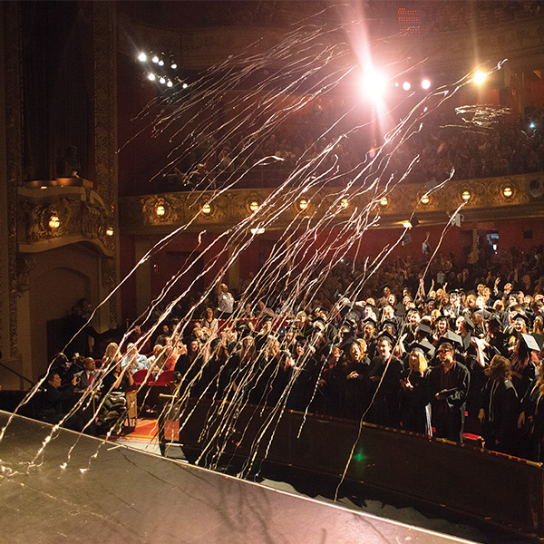 A group of graduating students celebrates in an auditorium